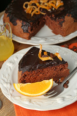 Cake with Chocolate Glaze and orange on plate, on wooden background
