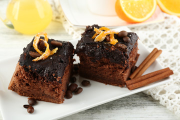 Piece of Cake with Chocolate Glaze and orange on plate, on wooden background