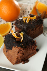 Portion of Cake with Chocolate Glaze and orange on plate, on wooden background