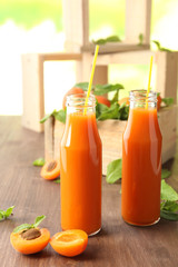 Bottles of apricot juice and fresh fruits on table close up