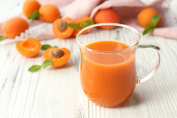 Cup of apricot juice and fresh fruits on table close up