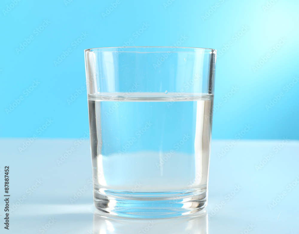 Wall mural glass of water on blue background