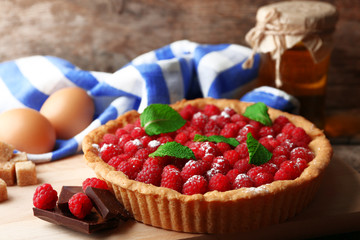 Tart with fresh raspberries, on wooden background