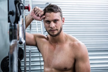 Fototapeta na wymiar Portrait of muscular man leaning against gym equipment