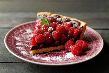 Piece of tart with fresh raspberries, on wooden background