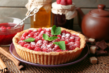 Piece of tart with fresh raspberries, on wooden background