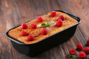 Fresh pie with raspberry in pan on wooden background