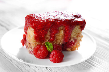 Fresh pie with raspberry jam in white saucer on wooden table, closeup