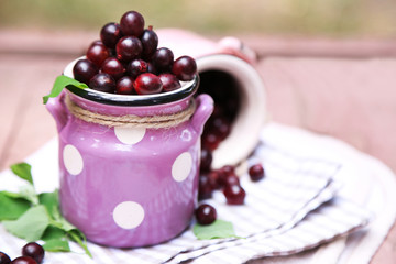 Red gooseberry in pail on wooden table close-up outdoors