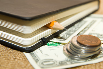 notebook, pencil and money on the old tissue