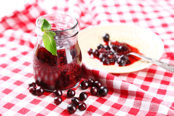 Jar of gooseberry jam on wooden table close-up