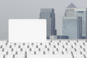 Blank white Credit card on a computer keyboard with Canary Wharf