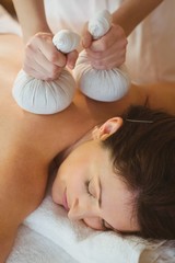 Obraz na płótnie Canvas Young woman getting herbal compress massage