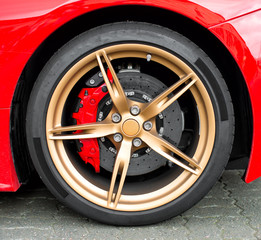 Red sports car wheel on the road.