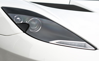 Close-up view of white sports car headlight.