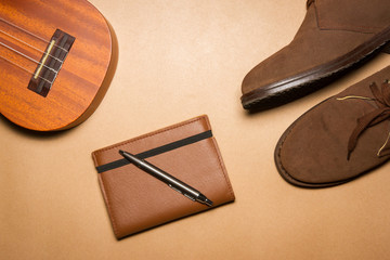 Notebook, pen , ukulele and boots on a brown paper background