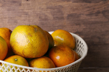 orange fruit in white basket on wood table background