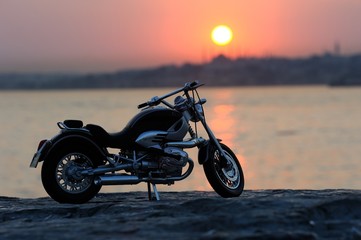 Naklejka premium Motorcycle on the rocks in sunset and golden hours
