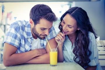 Obraz na płótnie Canvas Cute couple drinking an orange juice together 