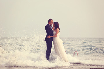 Bride and groom embracing at the beach