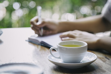 cup of tea with background of woman writing 
