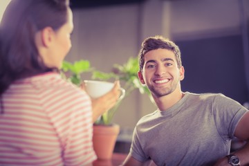 Smiling young man having coffee with his friend