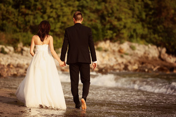 Bride and groom holding hands at the beach