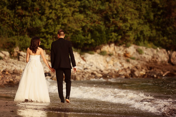 Bride and groom holding hands at the beach