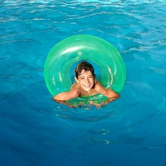 Niño en la piscina con flotador verde