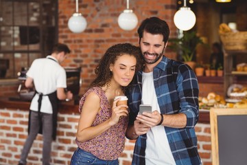 Smiling hipster couple looking at smartphone