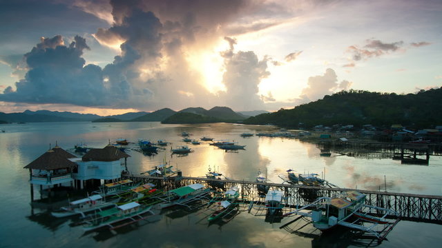 Sunset over Coron harbour timelapse, Coron, Palawan, Philippines. View on pier with traditional bangka boats
