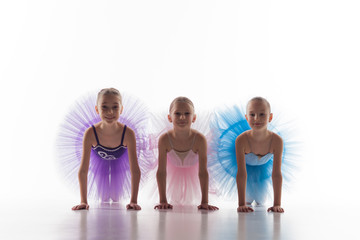 Three little ballet girls sitting in tutu and posing together