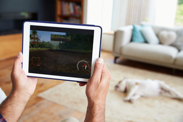 Close Up Of Man Playing Game On Digital Tablet At Home