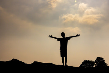 Silhouette of boy with hands raised