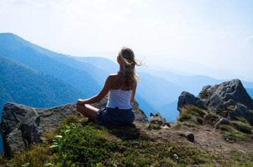 Naklejka na ściany i meble Young blond woman meditating in the beautiful mountain landscape