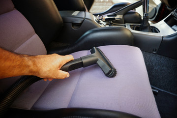 Hand vacuuming car interior.