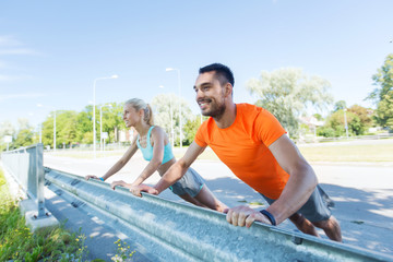 close up of happy couple doing push-ups outdoors