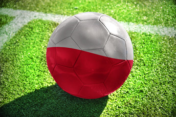 football ball with the national flag of poland lies on the green field near the white line