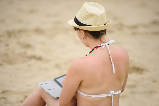 woman reading tablet reader on the beach