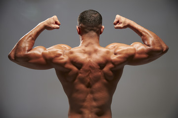 Fototapeta na wymiar Male bodybuilder flexing his biceps, back view