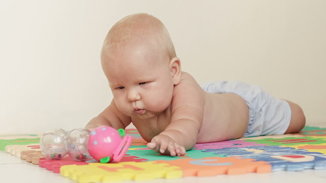 Baby boy plays with toy on light background