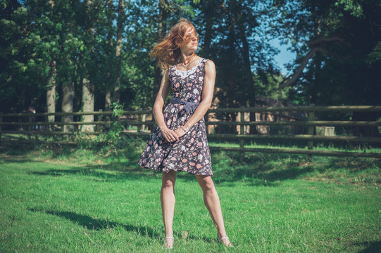 Young woman standing in field by fence on summer day