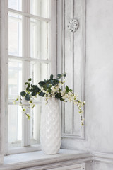 Still life with bouquet of artificial cherry blossoms in a chinese vase on the windowsill in white interiour