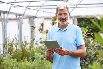 Portrait Of Sales Assistant In Garden Center With Digital Tablet