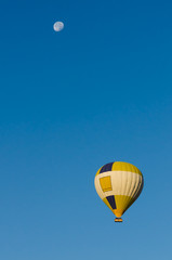 Hot Air Balloon flying over clear blue sky with Moon