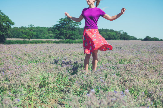 Happy young woman spinning in field of purple flowers