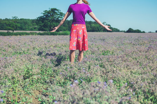 Woman raising her arms in a field of purple flowers