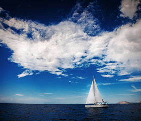 The white sails of yachts on the background of sea and sky in the clouds