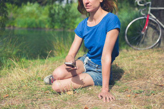 Young woman using smart phone by water in park