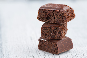 Porous dark chocolate on a white wooden background
